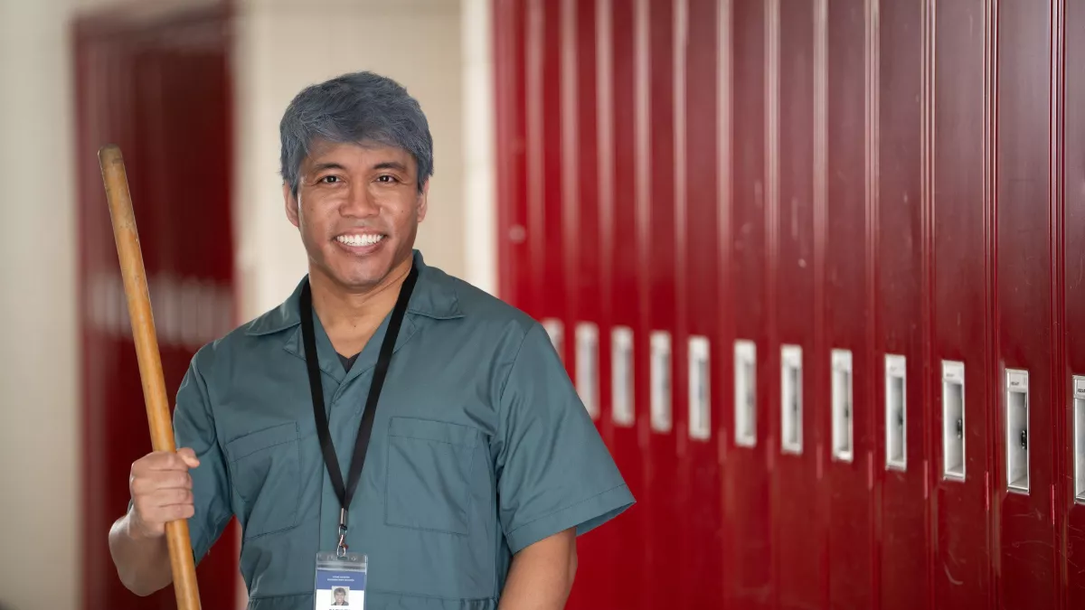 A custodian poses for a picture in a school hall