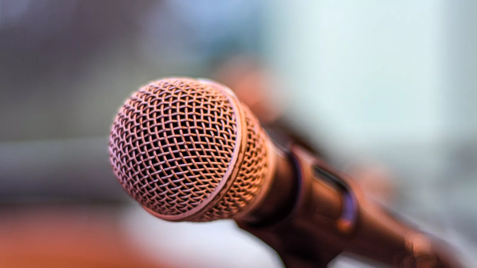 A shot of an in-focus microphone at the top of a microphone stand. background is out-of-focus.