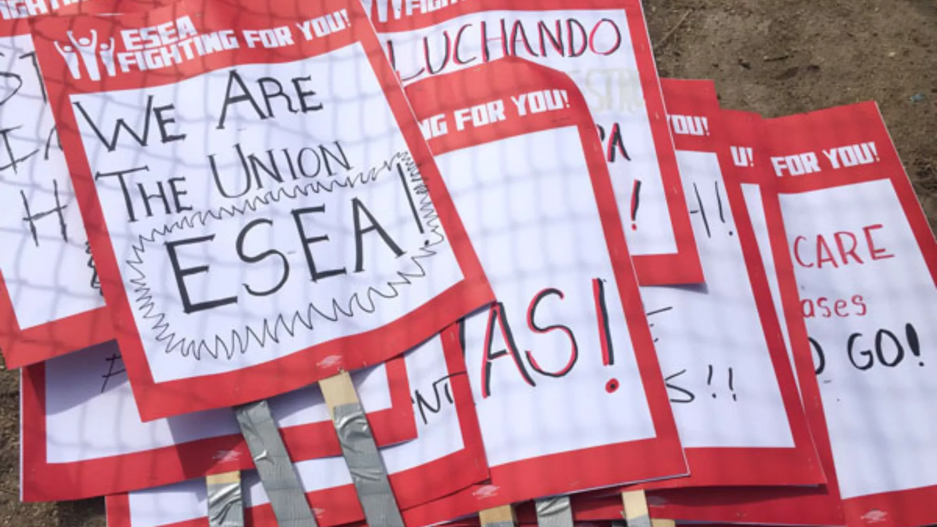 ESEA picket signs stacked on top of each other. The top sign reads "WE ARE THE UNION! ESEA!"